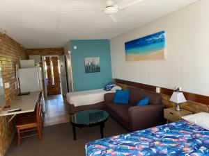Shelly Beach Motel في خليج هيرفي: غرفة نوم بسرير واريكة ومكتب