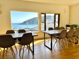 a room with a table and chairs and a large window at Guesthouse All you need in Shimoda