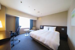 広島市にあるANAクラウンプラザホテル広島の大きなベッドとデスクが備わるホテルルームです。