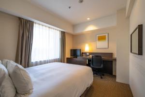 Cette chambre comprend un lit et un bureau avec un ordinateur. dans l'établissement ANA Crowne Plaza Hiroshima, an IHG Hotel, à Hiroshima