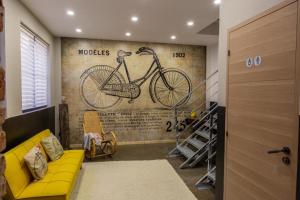 a living room with a yellow couch and a bike mural at Le Loft de l ancienne forge in Muhlbach-sur-Munster