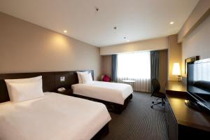 um quarto de hotel com duas camas e uma televisão de ecrã plano em ANA Crowne Plaza Hiroshima, an IHG Hotel em Hiroshima