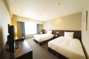 um quarto de hotel com duas camas e uma televisão em ANA Crowne Plaza Hiroshima, an IHG Hotel em Hiroshima