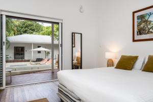 a bedroom with a white bed and a sliding glass door at Cove Studios in Byron Bay