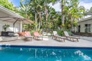 a pool with chairs and an umbrella next to a house at Cove Studios in Byron Bay