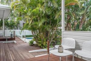 a patio with white chairs and palm trees at Cove Studios in Byron Bay