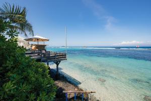 a pier with an umbrella over the water at Pondok Pisang Candidasa in Candidasa