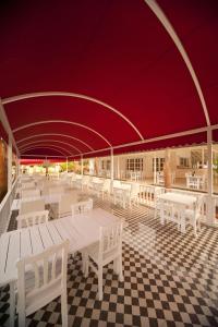 una cafetería con mesas y sillas blancas y techo rojo en White Hotel, en Ölüdeniz