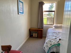ein kleines Schlafzimmer mit einem Bett und einem Fenster in der Unterkunft The Cottage @ Aranui in Wairoa
