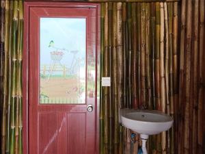 a bathroom with a sink and a red door at Bansuanphutarn in Ban Pha Saeng Lang