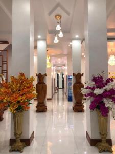 a hallway with vases of flowers in a building at HOTEL ĐĂNG KHOA 1 NÚI SAM in Chau Doc