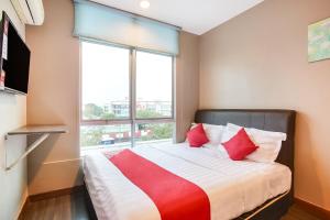 um quarto com uma cama com almofadas vermelhas e uma janela em OYO 90282 Hotel Taj Inn, Seksyen 7 em Shah Alam