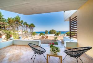 un patio con 2 sedie, un tavolo e l'oceano di FLUO Seaside Apartment a Vathí