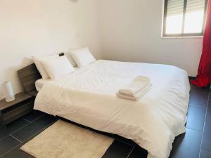 a white bed with two towels on top of it at Albufeira Beach side Apartment in Albufeira