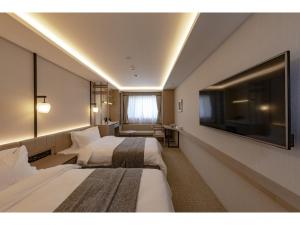 a hotel room with two beds and a flat screen tv at Yukari no Mori in Fujikawaguchiko