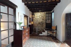 uma sala de estar com uma cómoda e uma parede de pedra em La casa del piano - Beautiful 18th century house with courtyard & pool em Jimena de la Frontera