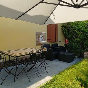 un patio con mesa, sillas y sombrilla en Soggiorno in Relax, en Correggioverde