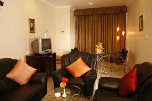 a living room with black leather furniture and a television at CLUB7 HOTEL in Thiruvalla