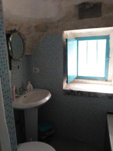 een badkamer met een wastafel en een toilet en een raam bij Trullo Francisco in Martina Franca