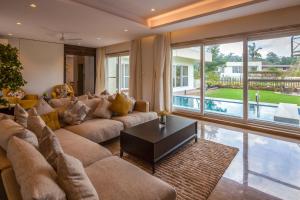 a living room with a large couch and a table at Villa Azul by StayVista, offering A snooker table, Terrace, Swimming pool & A spacious lawn with a charming gazebo for a perfect getaway in Lonavala