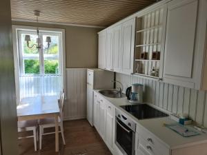 a kitchen with white cabinets and a sink and a window at Lahe Guesthouse in Haapsalu