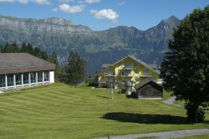 a large yard with a building and mountains in the background at Haus Mezzaselva - CharmingStay in Flumserberg