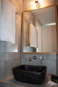 La salle de bains est pourvue d'un lavabo noir et d'un miroir. dans l'établissement AGNADEMA Luxury Residences, à Schinoussa