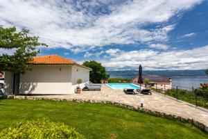 a backyard with a swimming pool and a house at Apartment MAGAŠ in Vrbnik