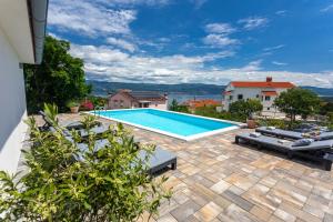 a swimming pool with chaise lounge chairs on a patio at Apartment MAGAŠ in Vrbnik