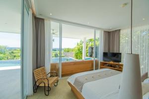 a bedroom with a bed and a tv and a balcony at Deep Blue Villa Bali in Umeanyar
