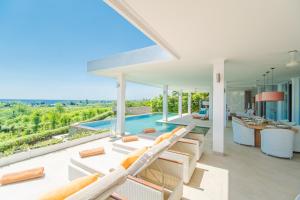 an open living room with white furniture and a swimming pool at Deep Blue Villa Bali in Umeanyar