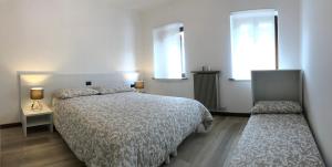 1 dormitorio con 1 cama y 2 ventanas en Alle Schiette, en Ponte nellʼAlpi