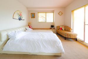 1 dormitorio con cama blanca y sofá en Hakone Villa en Hakone