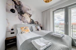 a bedroom with a bed and a large window at Live & Travel Apartments Grano Residence in Gdańsk