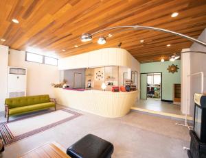 a living room with a green couch and a kitchen at tune Hostel（ツネホステル館山） in Tateyama