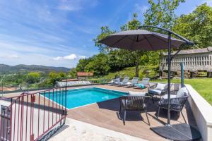 una piscina con sombrilla y sillas y un patio con mesa. en Casa Costiña, en Cotobade