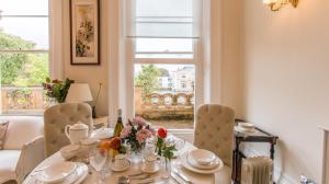 comedor con mesa, sillas y ventana en Flat 3, 6 Lypiatt Terrace Cheltenham Gloucestershire GL50 2SX en Cheltenham
