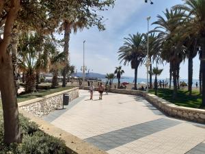 dwoje ludzi spacerujących po chodniku w pobliżu plaży w obiekcie Apartamento Eursu Playa w Maladze