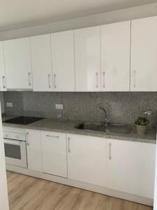 a kitchen with white cabinets and a sink at PERLA DEL SOL in Torremolinos