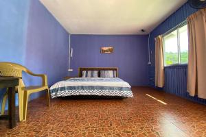a blue bedroom with a bed and a chair at OYO 90284 Kampung Stay Kilimu in Ranau