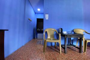 dwa krzesła i stół w pokoju z niebieską ścianą w obiekcie OYO 90284 Kampung Stay Kilimu w mieście Ranau