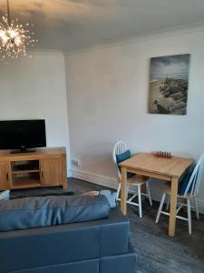 a living room with a couch and a table at Beachmount Holiday Apartments in Colwyn Bay
