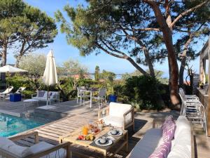 un patio con mesa y sillas junto a una piscina en Les Suites d'Agosta en Porticcio