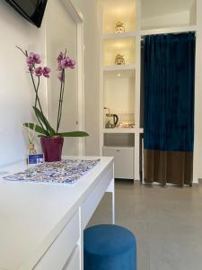 un tavolo bianco con un vaso con fiori viola di CIVITAS a Catania