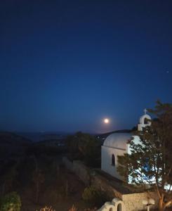 uma igreja branca à noite com a lua no céu em AGNADEMA Luxury Residences em Skhoinoussa