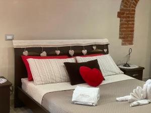 a bed with a red heart pillow on it at Corte Navari - GuestHouse Fred in Pietrasanta