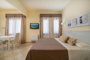 a bedroom with a bed and a table and a desk at Hotel Regina Elena in Olbia
