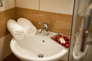 zlew w łazience z ręcznikami i tacą z jedzeniem w obiekcie Hotel Class Hermannstadt w Sybinie