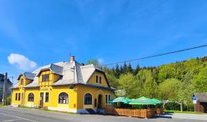 una casa amarilla al lado de una calle en Penzion U Kovárny, en Malá Morávka