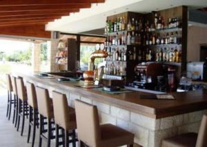 a bar with chairs and a counter with alcohol bottles at Nostos Hotel in Afitos